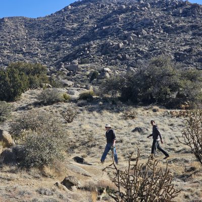 Hikers walking through rocky desert landscape.