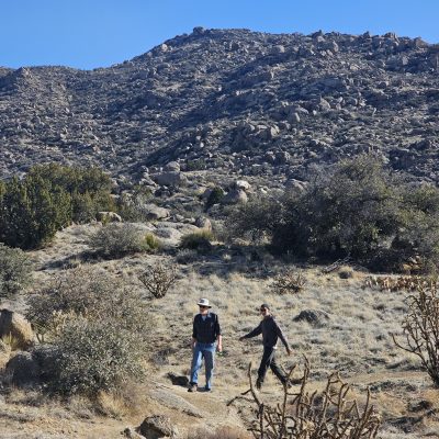 Two hikers on rocky desert trail.