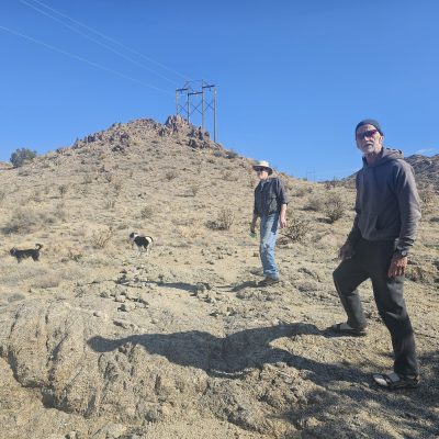 Two people and dogs hiking in rocky desert area.