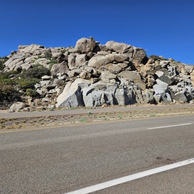 Highway view with rocky hillside and clear sky.