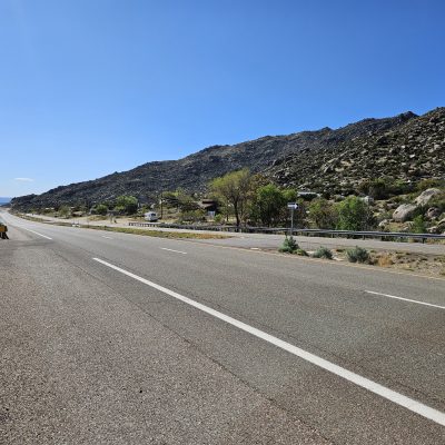Desert highway with mountains under clear blue sky.
