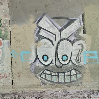 Cartoon face graffiti on concrete wall.