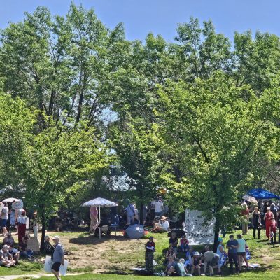 People gathered in park with banners and trees.