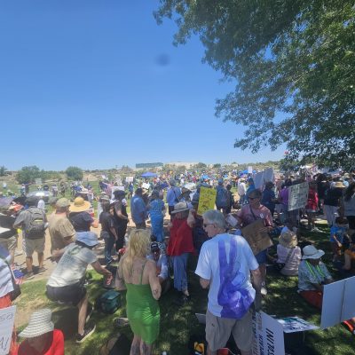 Large crowd holding signs at outdoor event.