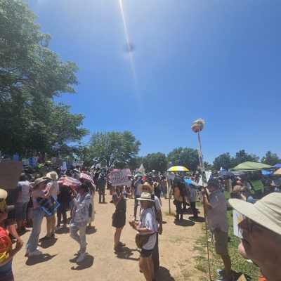 Large outdoor protest with signs and umbrellas.