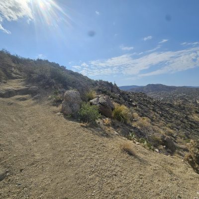 Desert hiking trail under sunny blue sky.