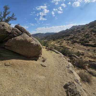 Desert landscape with rocks and distant mountains.