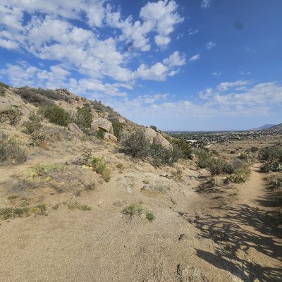 Trail through desert landscape with rocky hills.